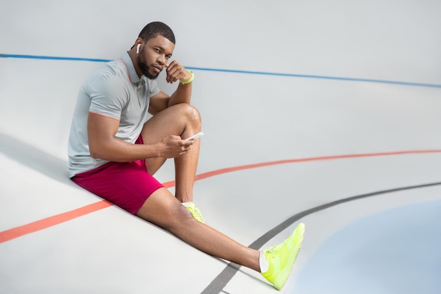 Photo calm handsome young male athlete with a smartphone