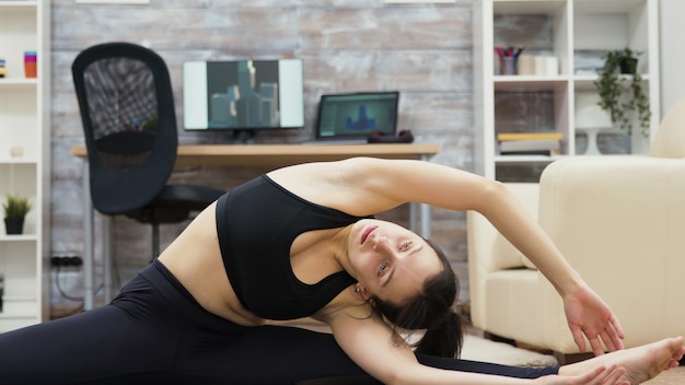 Calm and healthy young woman practicing yoga in living room.