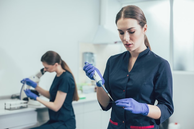 Calm lab assistant wearing rubber gloves and carefully holding a microscope slide