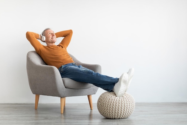 Calm mature man having rest at home listening to music