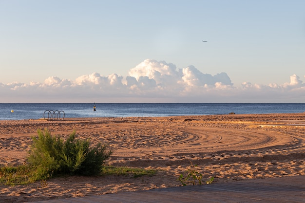 Foto mattina calma sulla spiaggia vuota con una gomma di auto stampe sulla sabbia, con mare e nuvole sullo sfondo