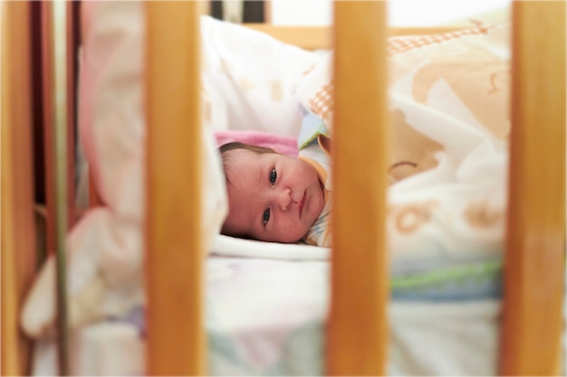 Calm newborn baby laying in her crib