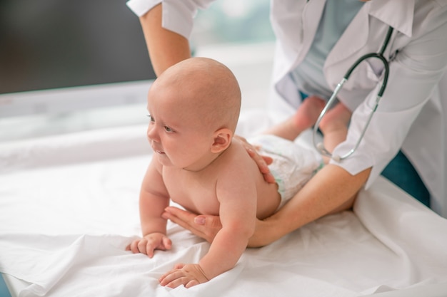 Calm newborn being examined by a female doctor