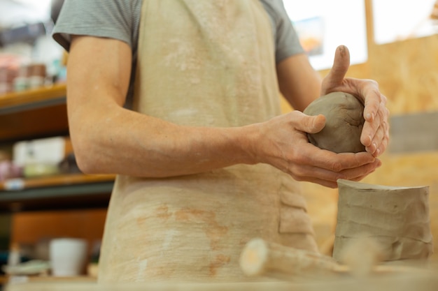 Calm professional master. Skilled master with strong hands rolling clay into right ball while working in studio