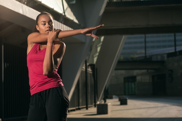 Calm professional sportswoman standing outdoors alone and warming up before the sports training. Template banner