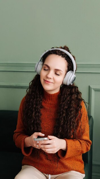 A calm relaxed carefree young woman listens to music an audio podcast or audiobook on her cell phone