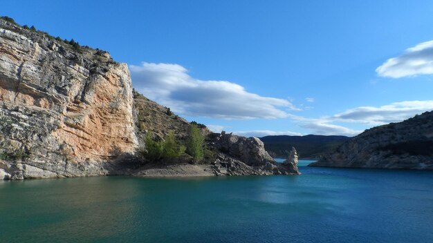 Calm sea against rocky coastal feature against blue sky