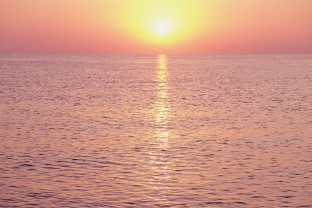 穏やかな海の水は昇る太陽の光に照らされています