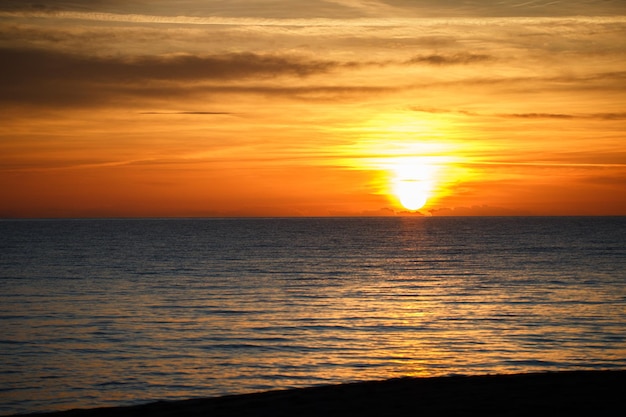 Calm sea with sunset sky and sun through the clouds over. Meditation ocean and sky background. Tranquil seascape