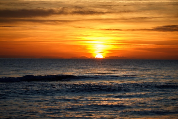 Calm sea with sunset sky and sun through the clouds over. Meditation ocean and sky background. Tranquil seascape