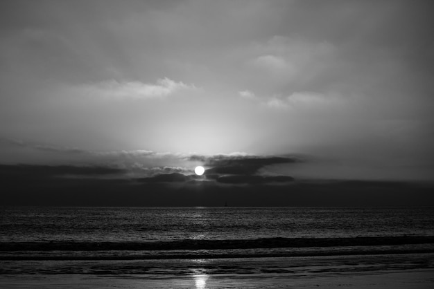 Calm sea with sunset sky and sun through the clouds over ocean and sky background seascape