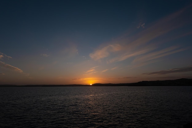 海の上の雲の切れ間から夕焼け空と太陽と穏やかな海