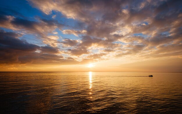 夕焼け空と雲の切れ間から太陽と穏やかな海