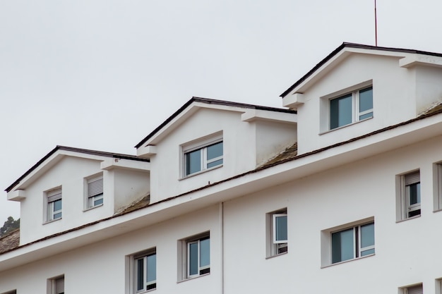 Calm shot of dormers on a white building roof with blue reflective windows