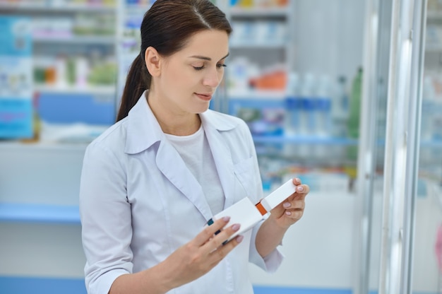 Calm smiling woman looking at two packs of medicines