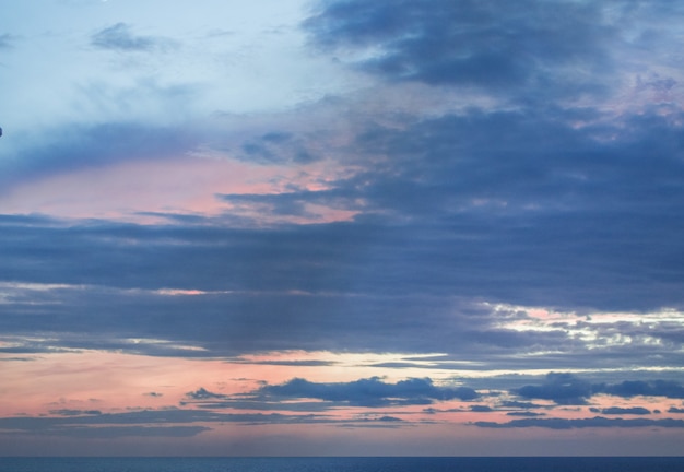 Calm sunset or sunrise over the Mediterranean sea, the sun shining through soft blue and pink clouds