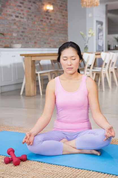 Donna calma che fa yoga sulla stuoia in salotto