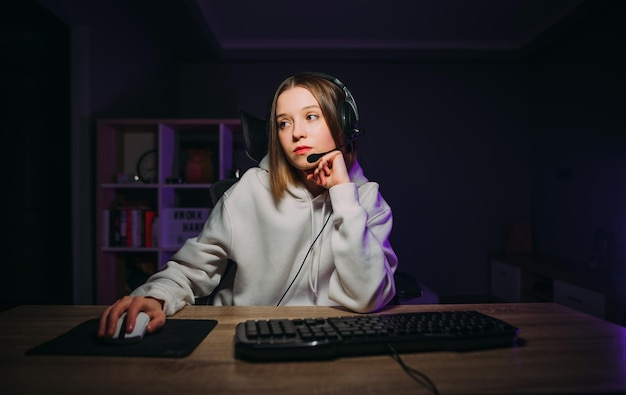 Donna calma con un auricolare seduto a casa al computer e giocando ai videogiochi online