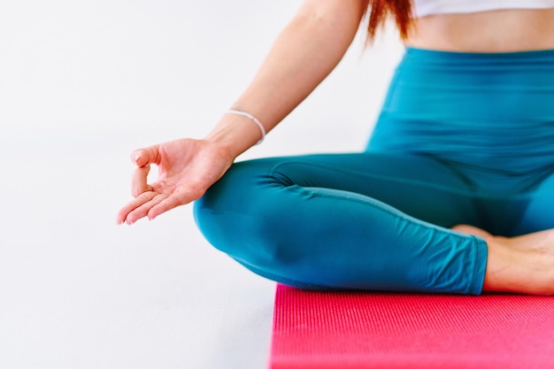 Foto donna calma con le mani di loto pratica l'esercizio di yoga sul tappetino in classe in studio