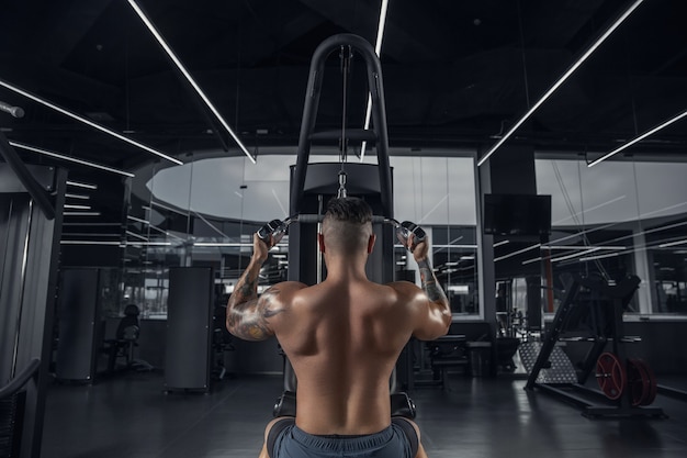Calm. Young muscular caucasian athlete practicing in gym with the weights. Male model doing strength exercises, training his upper body. Wellness, healthy lifestyle, bodybuilding concept.