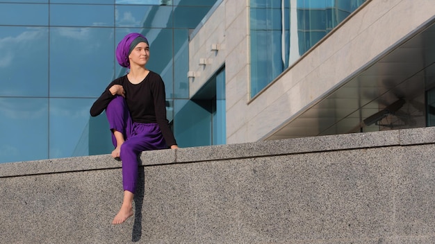 Calm young muslim girl buddist in hijab lonely lady female beautiful woman sits on building city