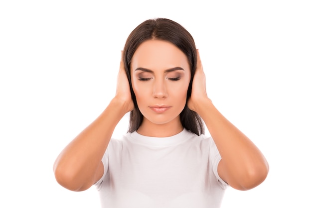 Calm young woman covering her ears and trying to focus