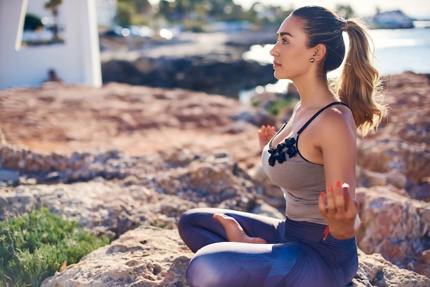 Calm young woman meditating on the rocks