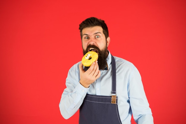 Calorie. Chef-kok voelt honger. Calorieën tellen. Dieet en gezonde voeding. calorie krijgen. Bebaarde man in chef-kok schort. Chef-kok in café. Voedsel calorie. bakker houdt donut. Grappige hipsterchef-kok. Alleen vers gebak.