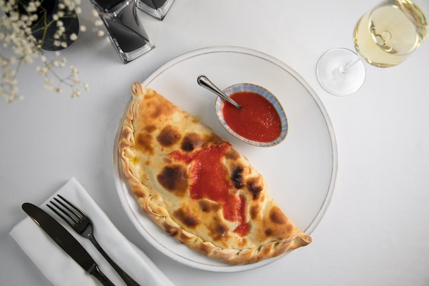 Calzone Eten en tomatensoep drinken op een witte tafel achtergrond witte kom op licht bord