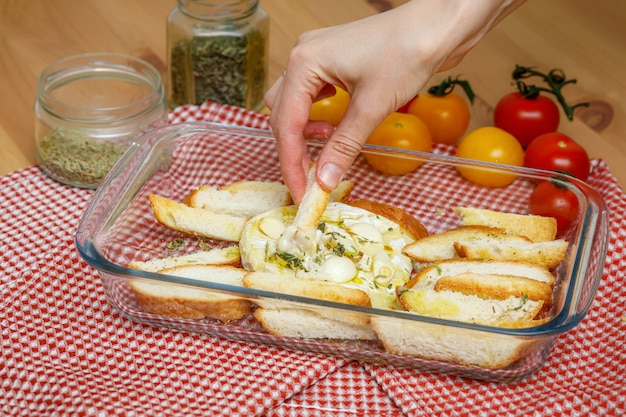 Camamber baked with garlic and spices. Hand dunking crispbread in melted cheese