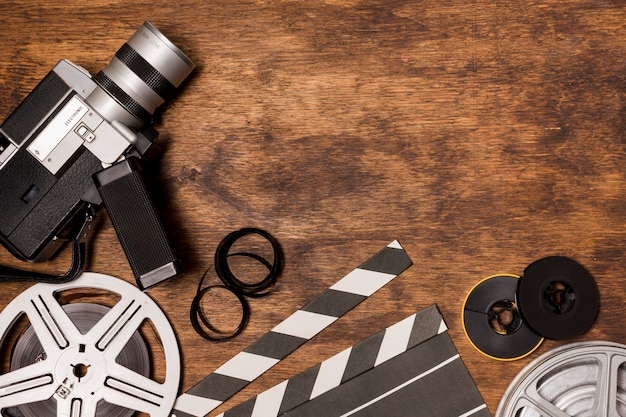フィルムリール付きビデオカメラ。カチンコ木製の背景上のフィルムストライプ