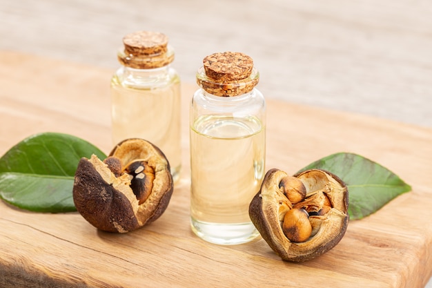 Camellia essential oil bottle and camellia seeds on wooden table. Beauty, skin care, wellness