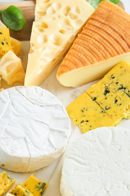 Camember and maasdam smoked cheese blue cheese parmesan brie cheese with basil and pepper on white marble board white wooden old background Set or assortment cheeses Top view Free copy space