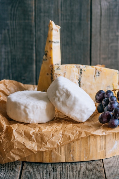 Photo camembert and blue cheese stilton with grapes. cheese plate on wooden background