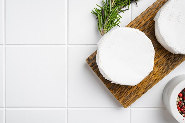 Camembert and brie cheese on white ceramic squared tile table background top view flat lay with copy space for text