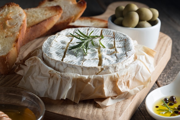 Camembert and brie cheese on wooden  with tomatoes, letuce and garlic. Italian food. Dairy products.