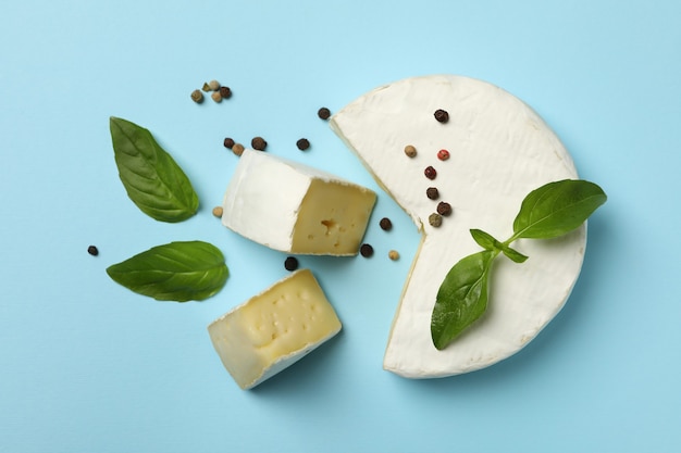 Camembert cheese, basil and pepper on blue background