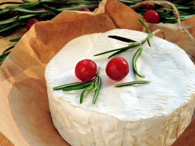 Camembert cheese in paper, cranberry and fresh rosemary.