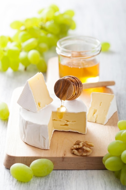 camembert cheese with grapes honey and nuts on wooden background