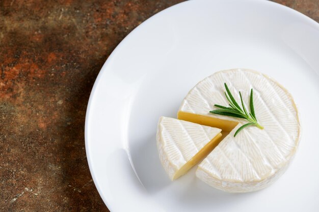 Camembert cheese with rosemary on white dish