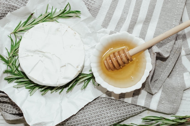 Camembert cheese with a sprig of rosemary and honey on the table