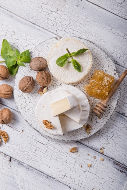 Camembert cheese on a wooden board with nuts, honey and mint.\
italian, french gourment