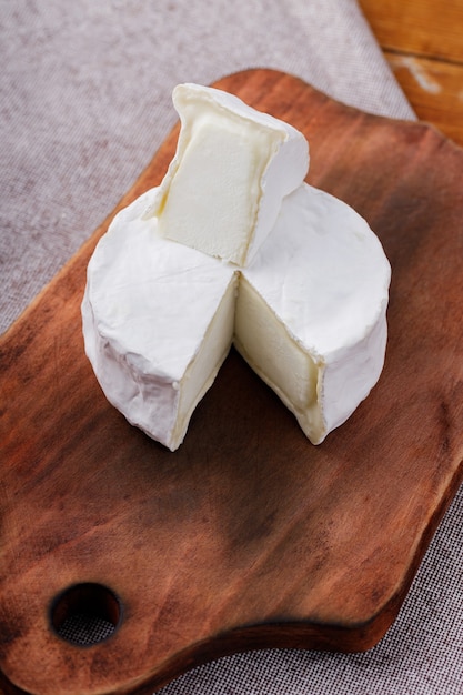 木製のまな板にカマンベールチーズ。木製の背景に白いチーズ。コピースペース