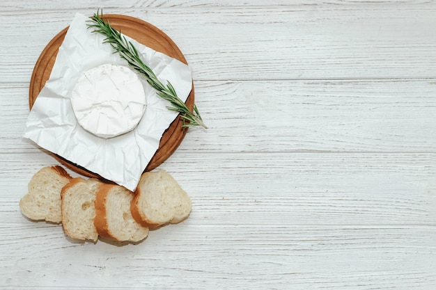 Camembert kaas met stokbrood croutons en een takje rozemarijn op tafel