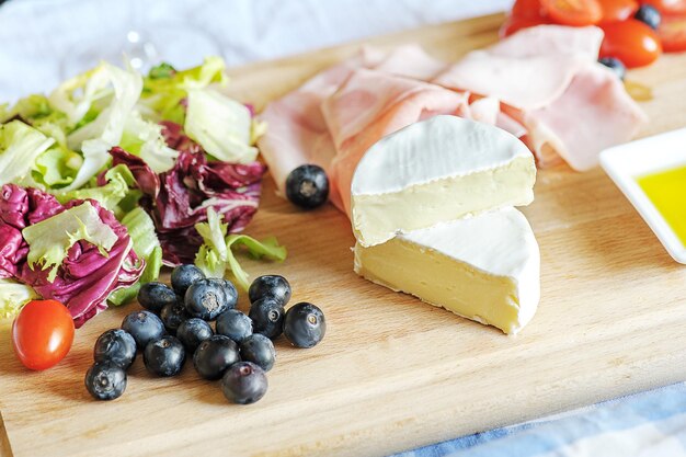 Camembert kaas op een serveerplank met groenten, vlees en bessen