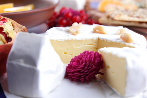 Camembert met noten en bessen op wit perkamentpapier Close-up van kaas met een roze bloem op een blauwe achtergrond