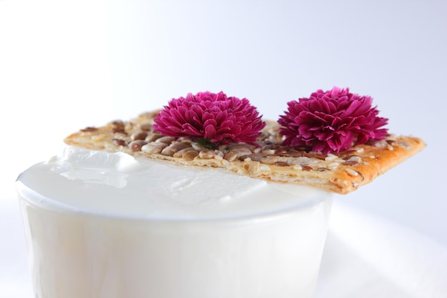 Camembert nuts berries and biscuits with seeds on white parchment paper Cheese with honey a glass of milk and a blue and white napkin on a light background Closeup