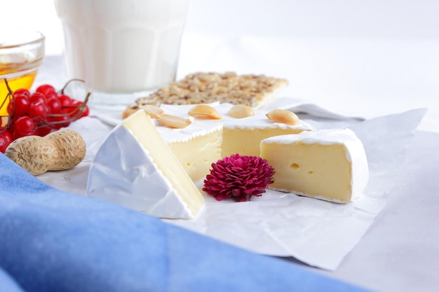 Camembert nuts berries honey a glass of milk and a cookie with seeds on a light background Breakfast food Closeup