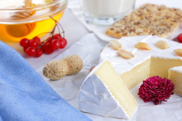 Camembert noci bacche miele un bicchiere di latte e un biscotto con semi su sfondo chiaro cibo per la colazione closeup