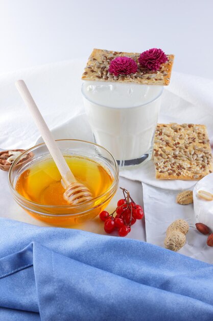 Camembert nuts berries honey a glass of milk and a cookie with seeds on a light background Breakfast food Closeup